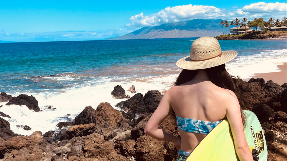 Female model wearing Hana Palm Straw Sun Hat, showcasing wide brim and eco-friendly materials.