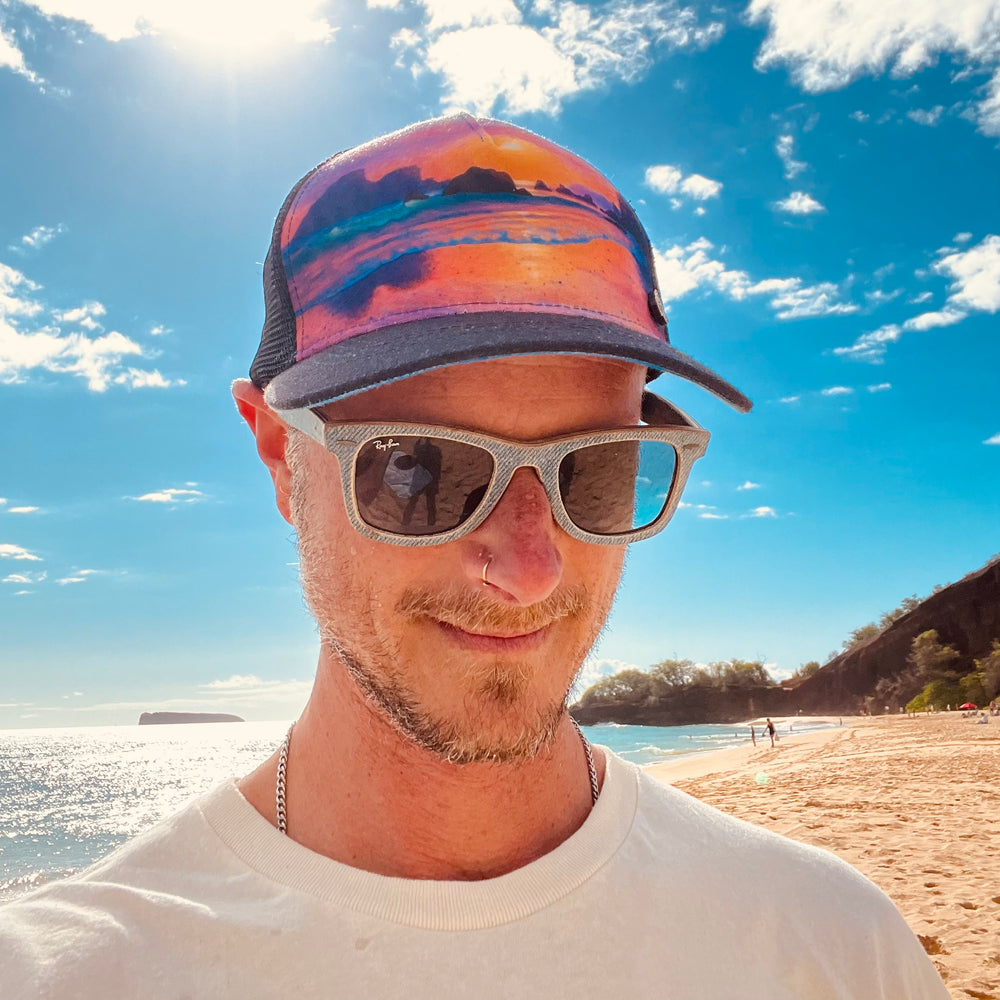 Male model styling the Horizon Trinidad Trucker Hat, featuring bold artwork, mesh back, and casual outdoor look.