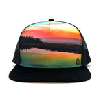 Front view of the Horizon Sunset Trucker Hat, featuring a Humboldt Bay sunset print, breathable mesh back, and adjustable snap closure.