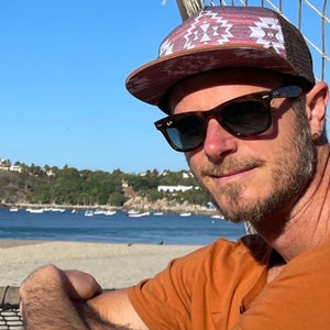 Male model styling the Nu Tribe Burgundy Trucker Hat, highlighting its adjustable fit, breathable mesh, and bold burgundy color.