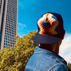 Male model styling the Santa Fe Trucker Hat, showcasing adjustable mesh back, southwestern graphic, and comfortable fit.