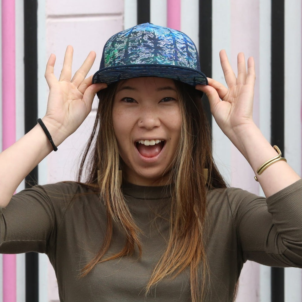 Female model wearing the Tree Trucker Hat, showcasing its fit and breathable mesh design.